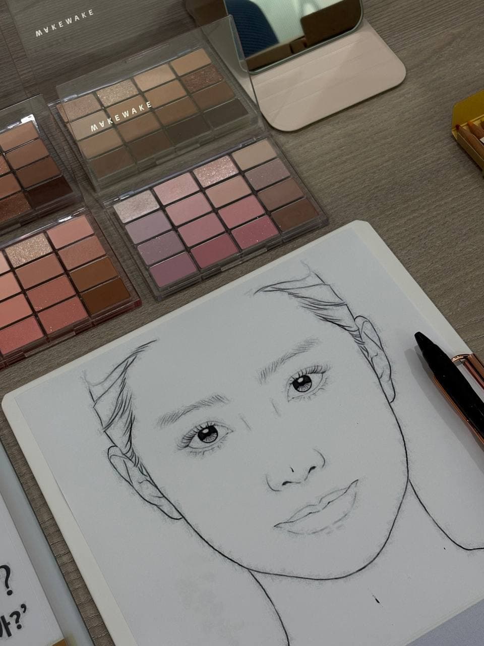 섀도 팔레트와 페이스 차트를 펼쳐 둔 상담 테이블